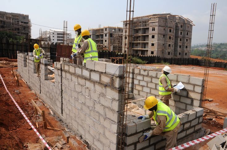 Workers laying concrete blocks on a construction site.